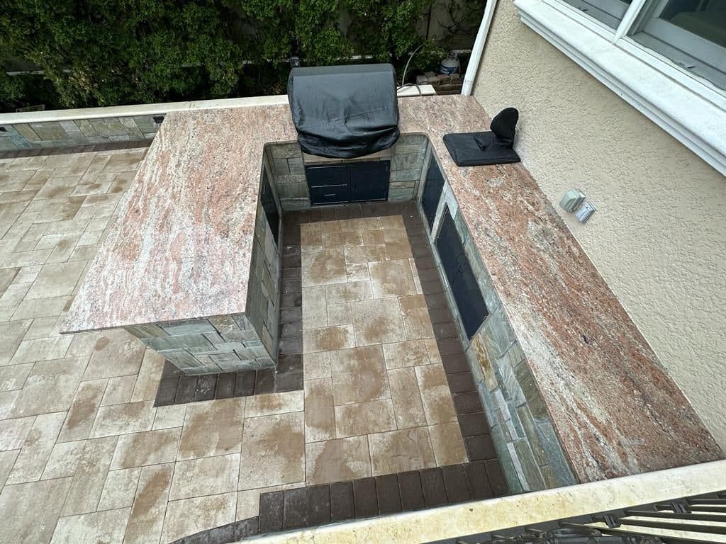 Stone-clad outdoor kitchen with granite countertops and a grill