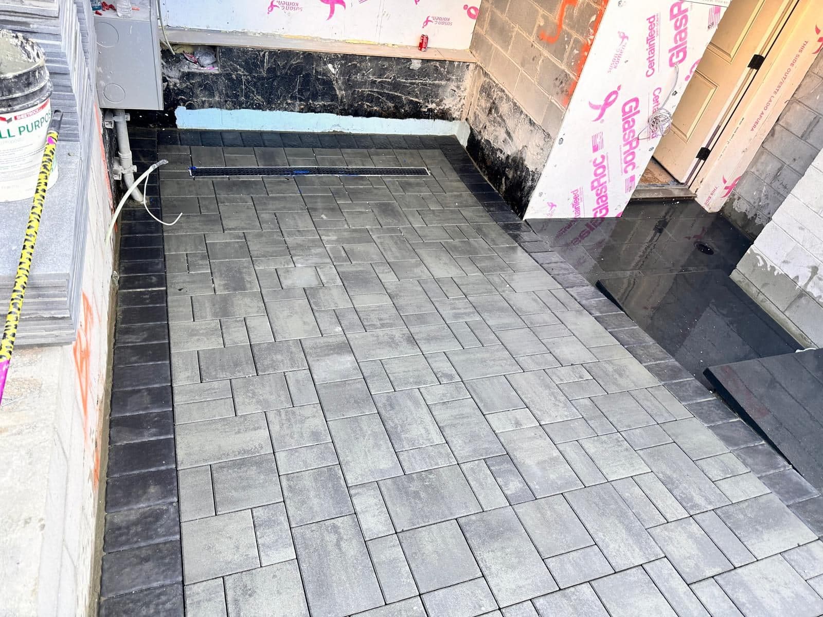 New dark-grey pavers between the house and the neighboring wall