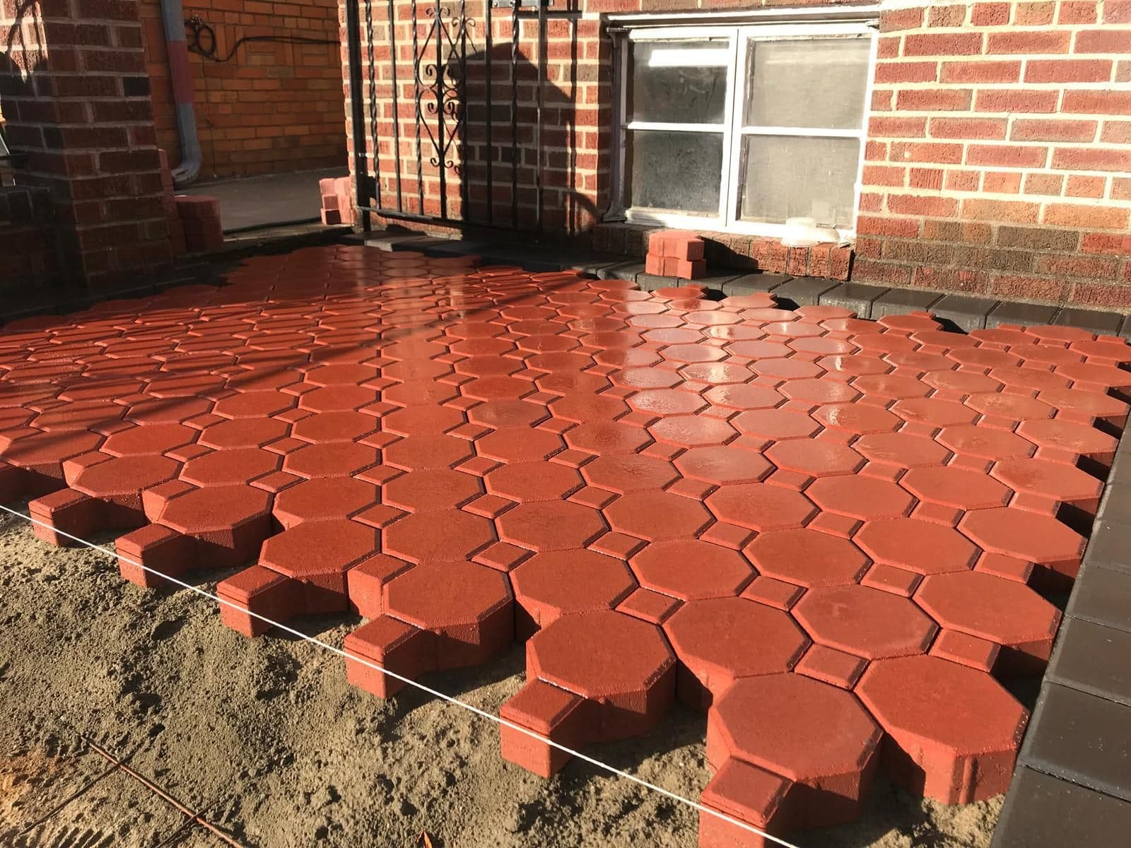 Red hexagon pavers being laid on the new base
