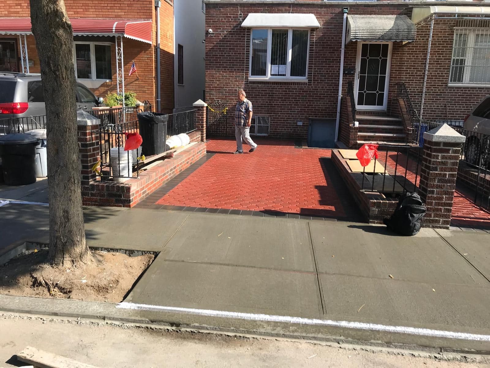 Red hexagon pavers next to a new concrete sidewalk in Brooklyn