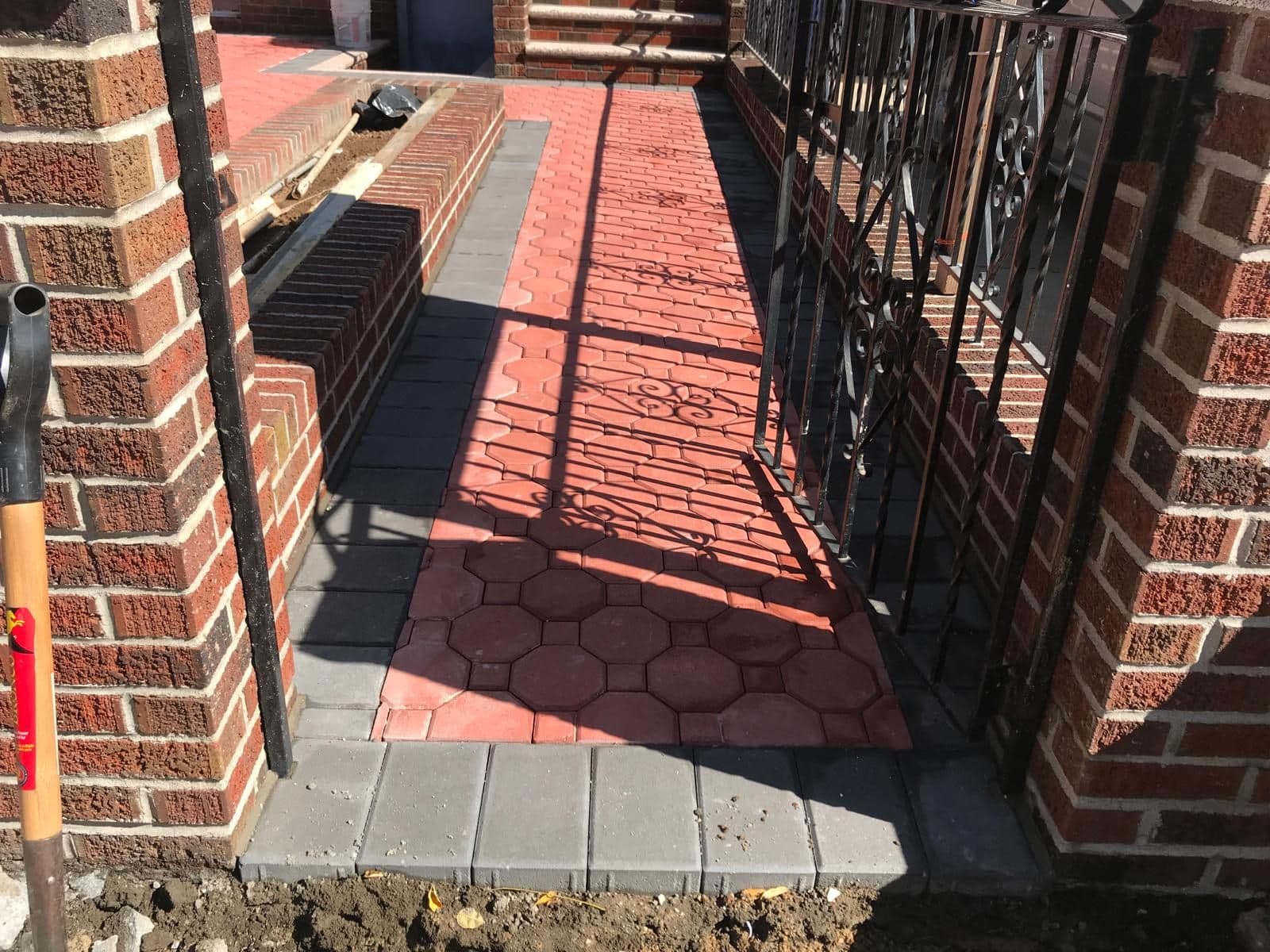 After: red hexagon pavers between the same brick pillars