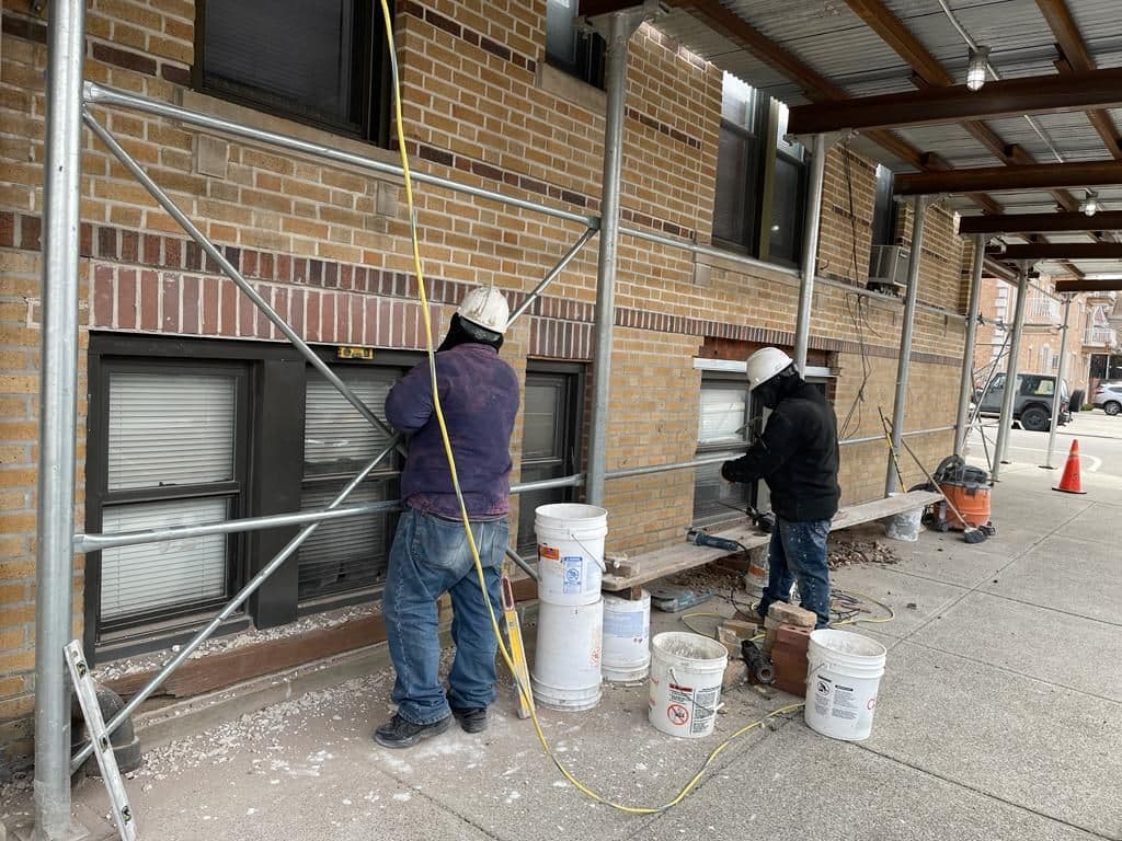 Crew pointing brick from a scaffold on a Brooklyn apartment building