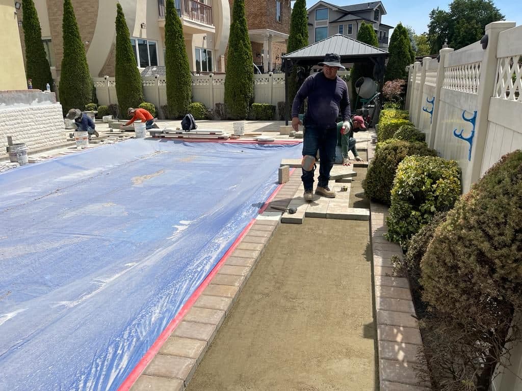 Crew laying pavers around the covered pool