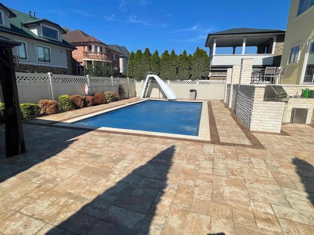 Finished pool deck in light stone pavers with a border