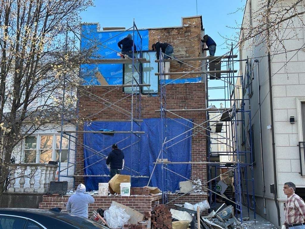 Home Developers NY crew on scaffolding building a new brick facade in Brooklyn