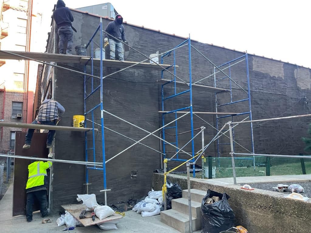 Crew on scaffolding applying the first coat