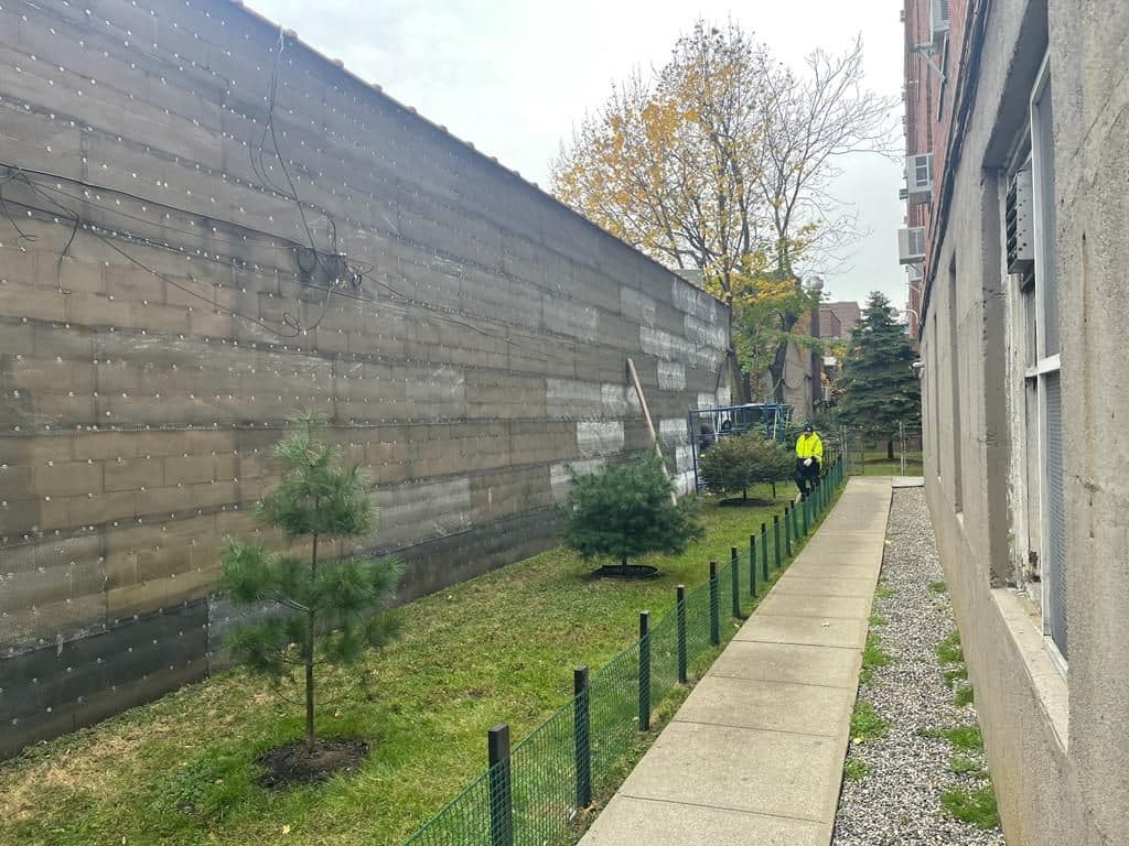 Before: long stained concrete-block wall along a walkway