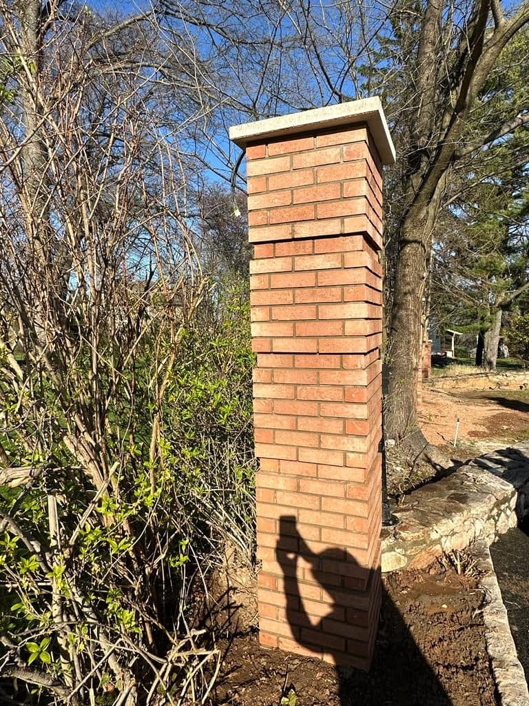 Capped brick column beside the stone wall
