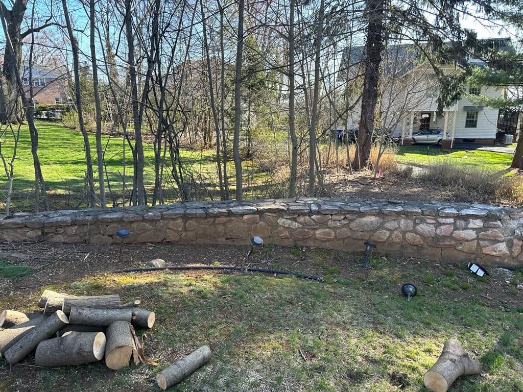 Before: open yard and old stone wall with no columns