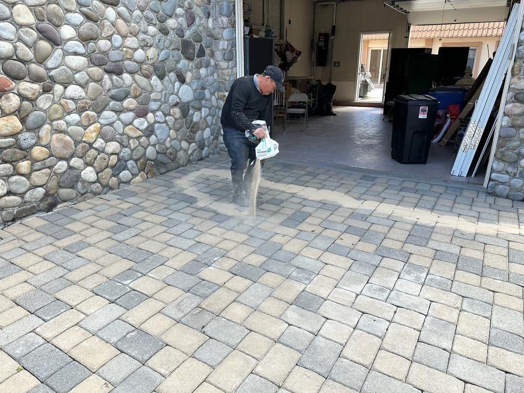 Worker spreading new sand into the paver joints
