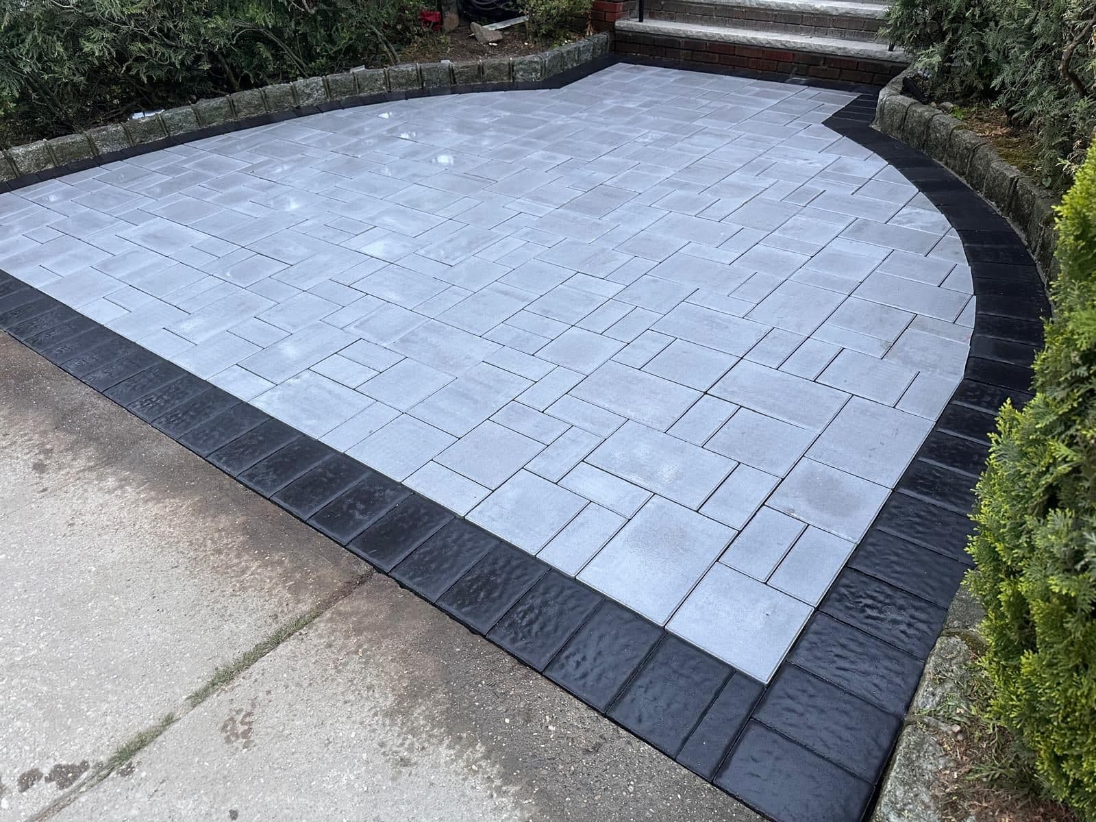 Grey pavers with a dark border along the planting beds